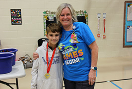  A woman stands with a boy wearing a medal